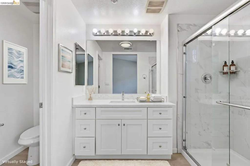 bathroom with vanity, a marble finish shower, and light wood-style floors - Virtually Staged