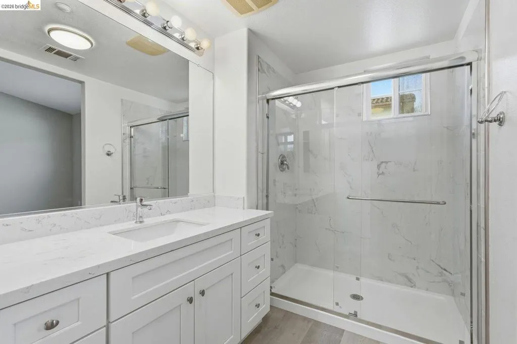 bathroom featuring vanity, a marble finish shower, and light wood-type flooring