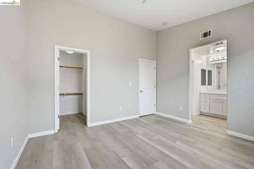 unfurnished bedroom featuring light wood-style flooring, a walk in closet, and connected bathroom