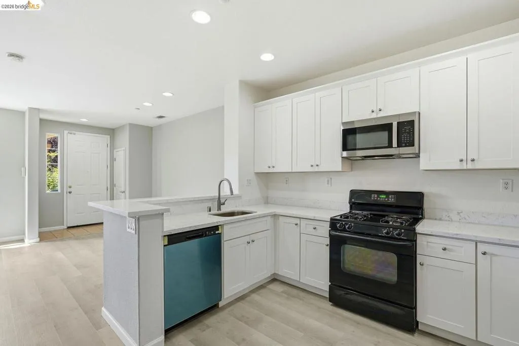 kitchen featuring black gas range, white cabinetry, stainless steel microwave, dishwashing machine, and recessed lighting