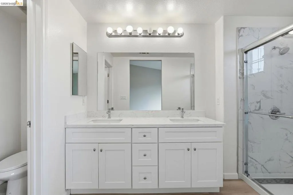 full bathroom featuring double vanity and a marble finish shower