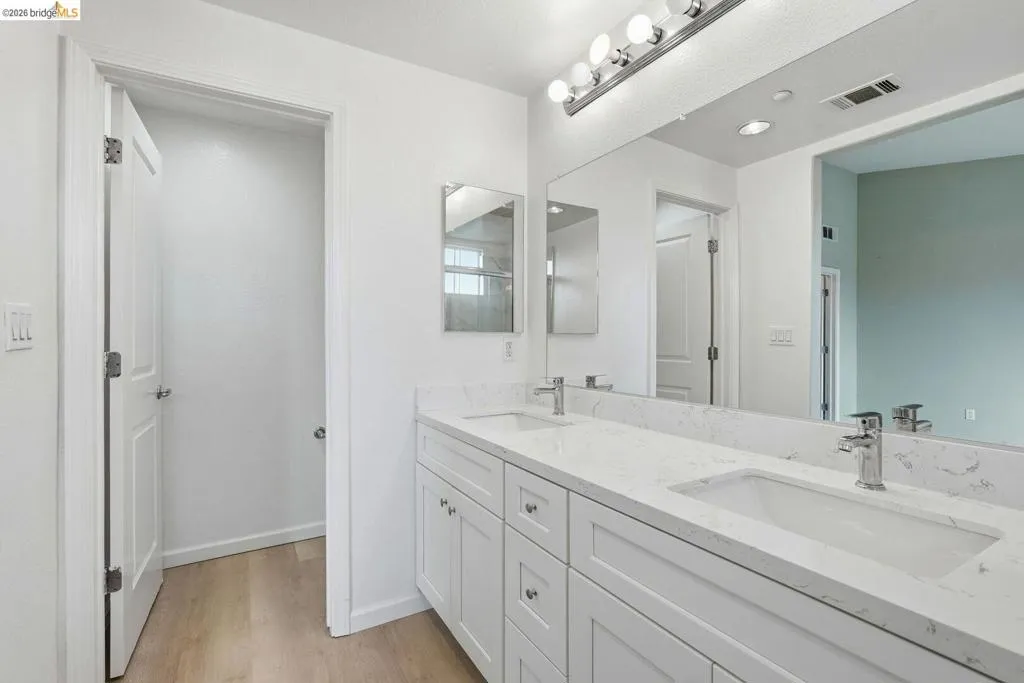 bathroom with double vanity and light wood-style flooring