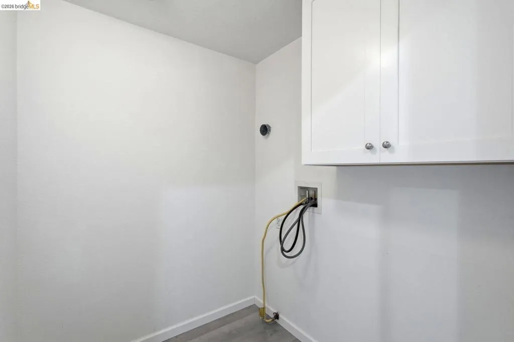 laundry area with hookup for a washing machine, cabinet space, and dark wood-type flooring