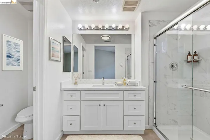 bathroom with vanity, a marble finish shower, and light wood-style floors - Virtually Staged