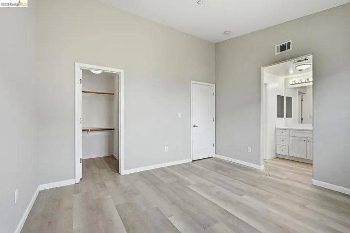 unfurnished bedroom featuring light wood-style flooring, a walk in closet, and connected bathroom