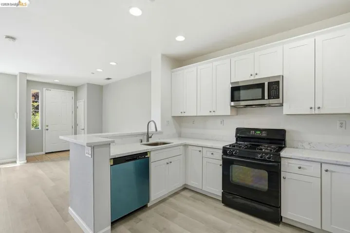 kitchen featuring black gas range, white cabinetry, stainless steel microwave, dishwashing machine, and recessed lighting