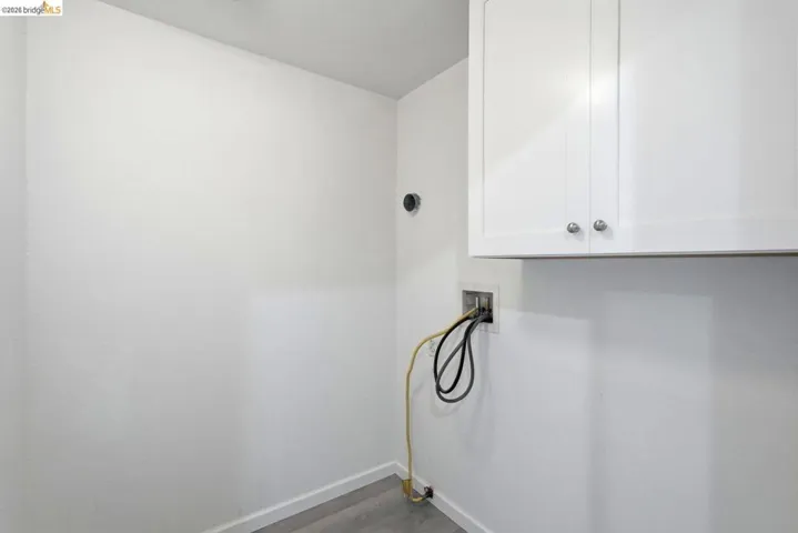 laundry area with hookup for a washing machine, cabinet space, and dark wood-type flooring