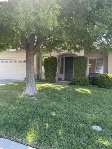 View of front of home with a front yard, a garage, stucco siding, and driveway