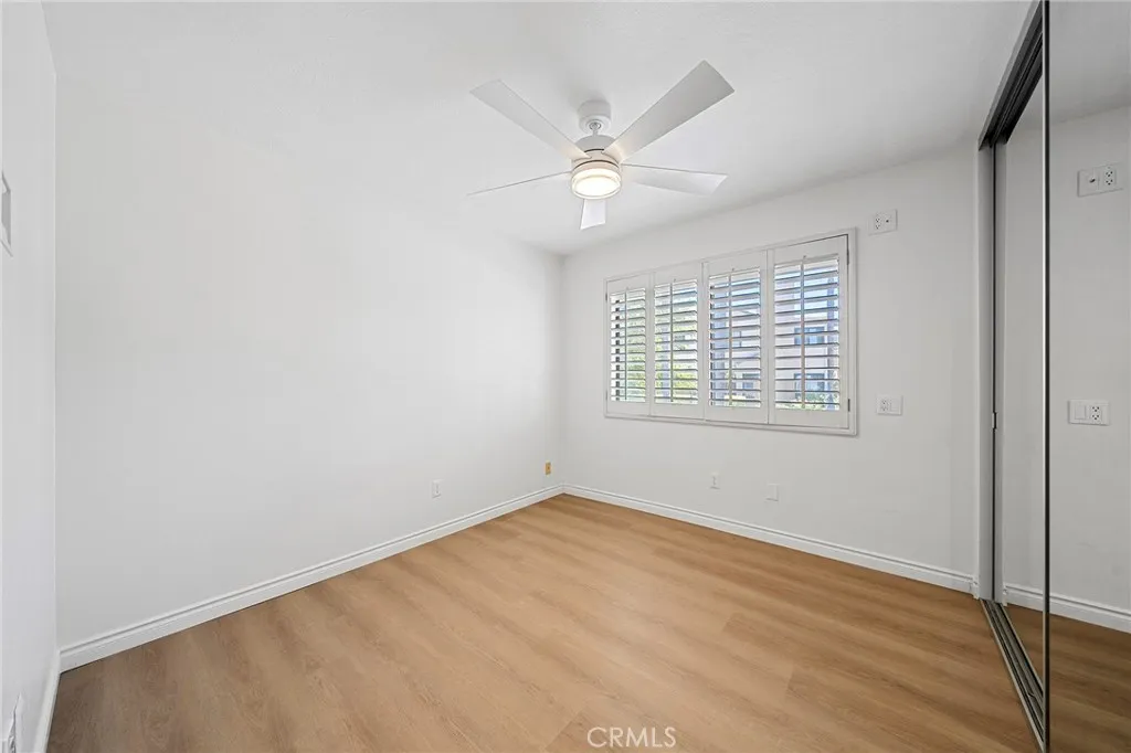 Second bedroom has spacious closet with custom organizers and sliding mirror doors. Plantation shutters and a ceiling fan.