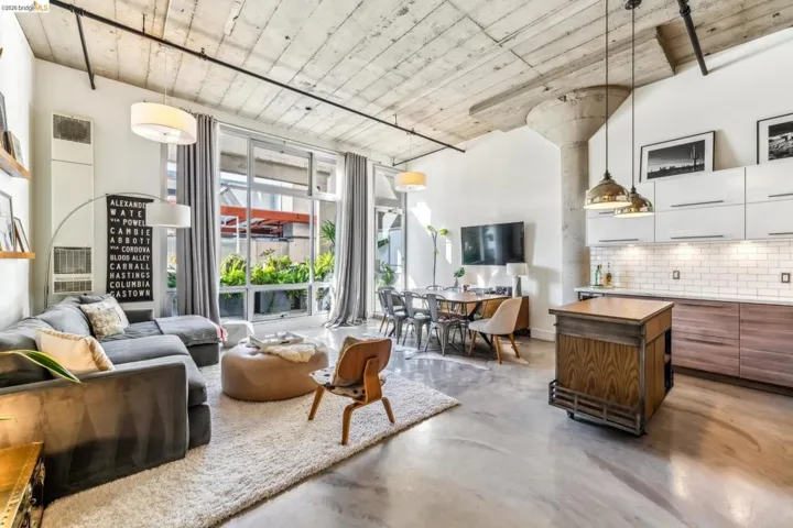 Open concept living area featuring concrete flooring, exposed concrete ceiling, industrial-style column, and full-height windows