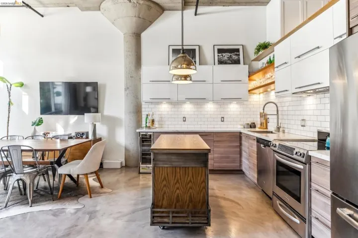 Open-concept living area featuring a modern kitchen with stainless steel appliances, white subway tile backsplash, and two-tone cabinetry