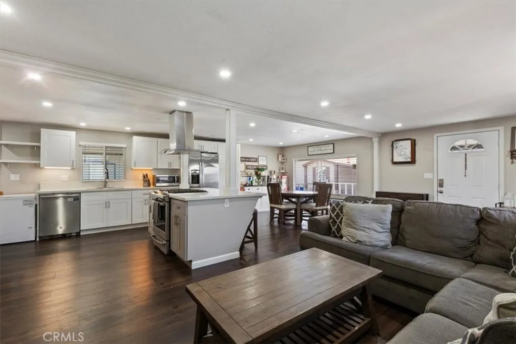 Updated Kitchen: Open island kitchen with white cabinetry, stainless steel appliances, bar seating, recessed lighting, and seamless flow to the living and dining areas.