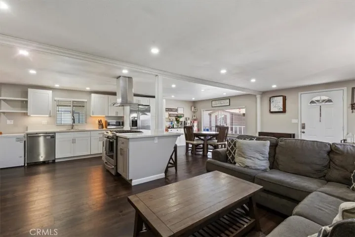 Updated Kitchen: Open island kitchen with white cabinetry, stainless steel appliances, bar seating, recessed lighting, and seamless flow to the living and dining areas.