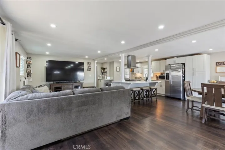 Living Room: Large open living area with updated flooring, recessed lighting, neutral tones, and direct flow to the kitchen and dining spaces.
