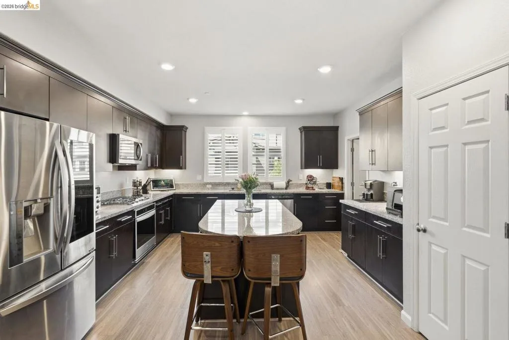 kitchen featuring stainless steel appliances, light stone countertops, a center island, light wood-type flooring, and recessed lighting