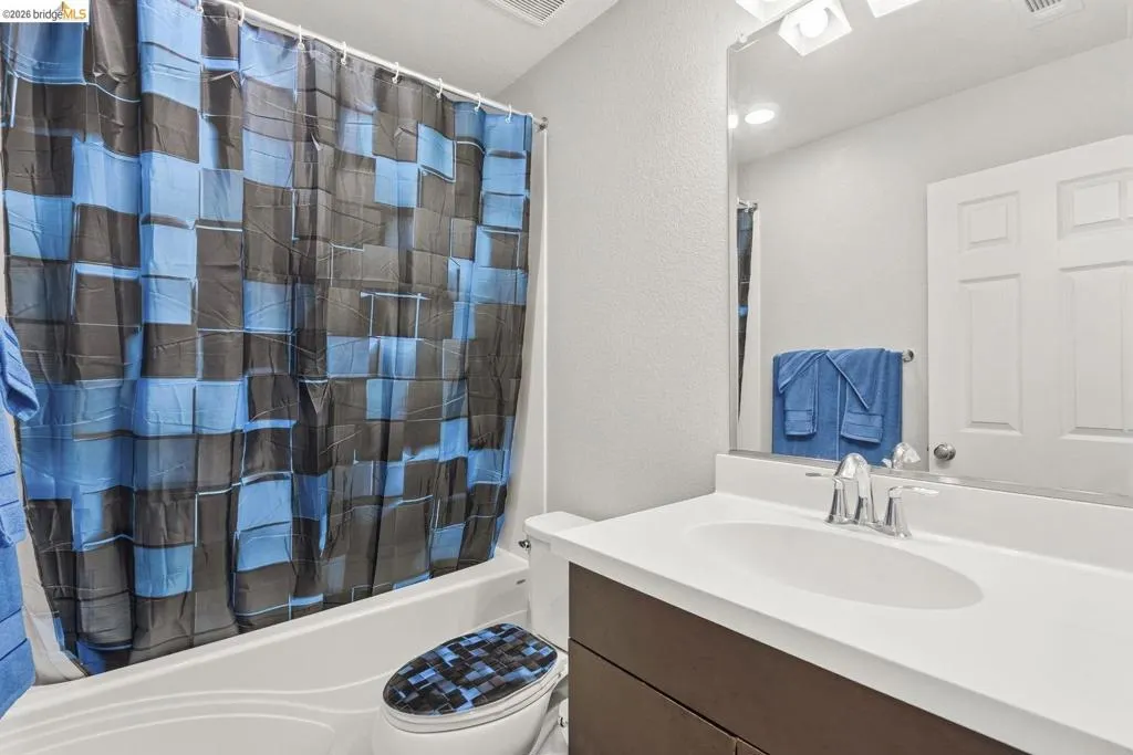 full bathroom featuring a textured wall, vanity, and shower / bath combo with shower curtain