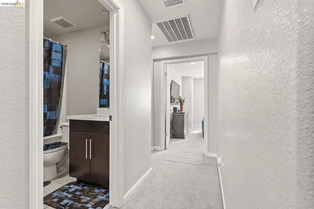 hallway featuring light colored carpet and a textured wall