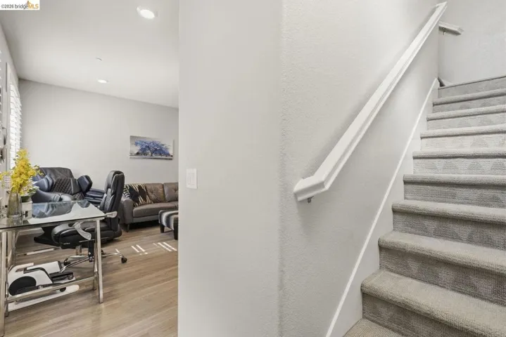 stairway featuring wood finished floors, recessed lighting, and a textured wall