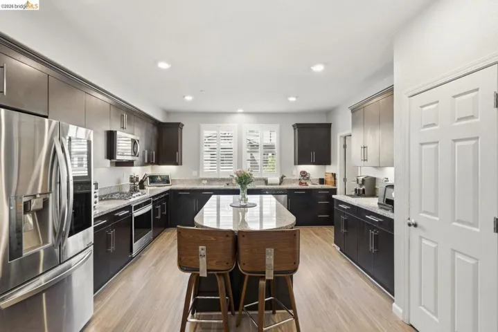 kitchen featuring stainless steel appliances, light stone countertops, a center island, light wood-type flooring, and recessed lighting