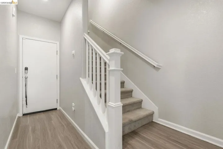 staircase featuring wood finished floors and a textured wall