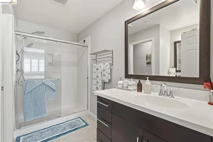 full bath with a shower stall, vanity, and light tile patterned floors