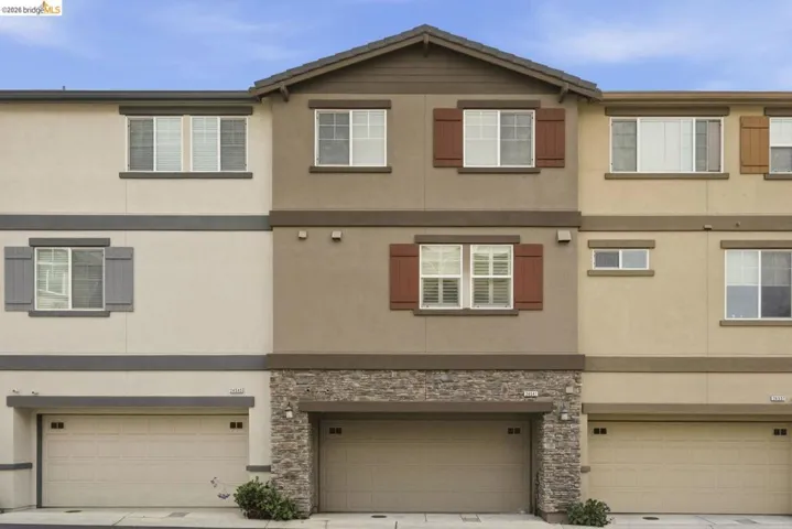 traditional-style house with stucco siding, a garage, driveway, and stone siding