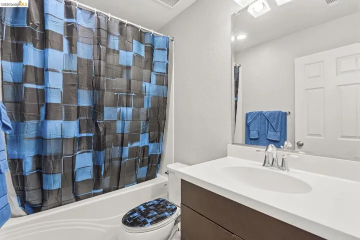full bathroom featuring a textured wall, vanity, and shower / bath combo with shower curtain