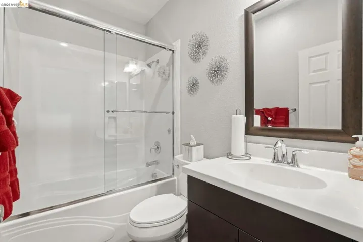 full bathroom featuring a textured wall, vanity, and combined bath / shower with glass door