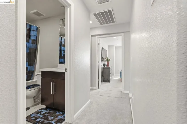 hallway featuring light colored carpet and a textured wall