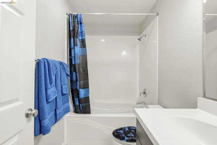 full bathroom featuring vanity, a textured wall, and shower / bath combo with shower curtain
