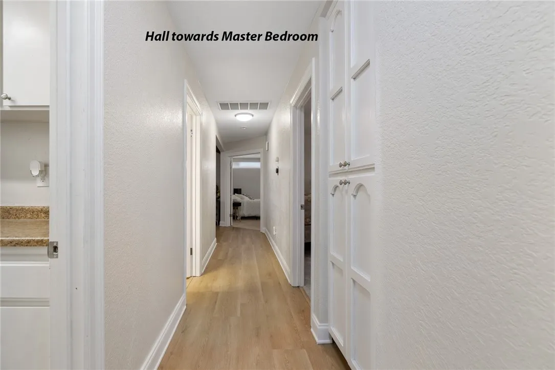Hall toward the primary suite. Laundry on the left, bedroom 3 on the right, guest bath on the left.