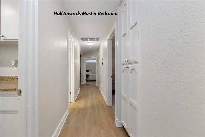 Hall toward the primary suite. Laundry on the left, bedroom 3 on the right, guest bath on the left.