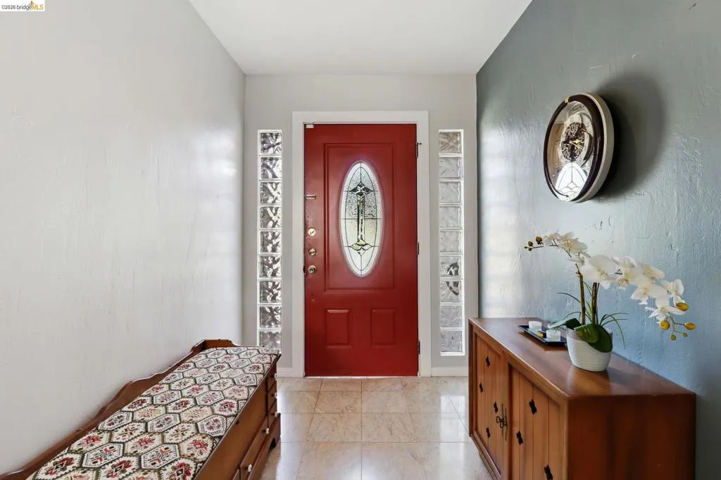Entryway featuring a red front door with leaded glass insert, flanked by glass block sidelights