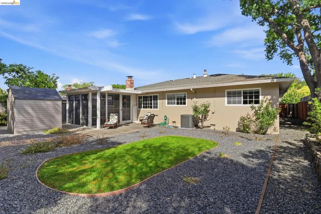 Rear exterior featuring a screened patio enclosure, concrete patio, and an oval-shaped lawn area