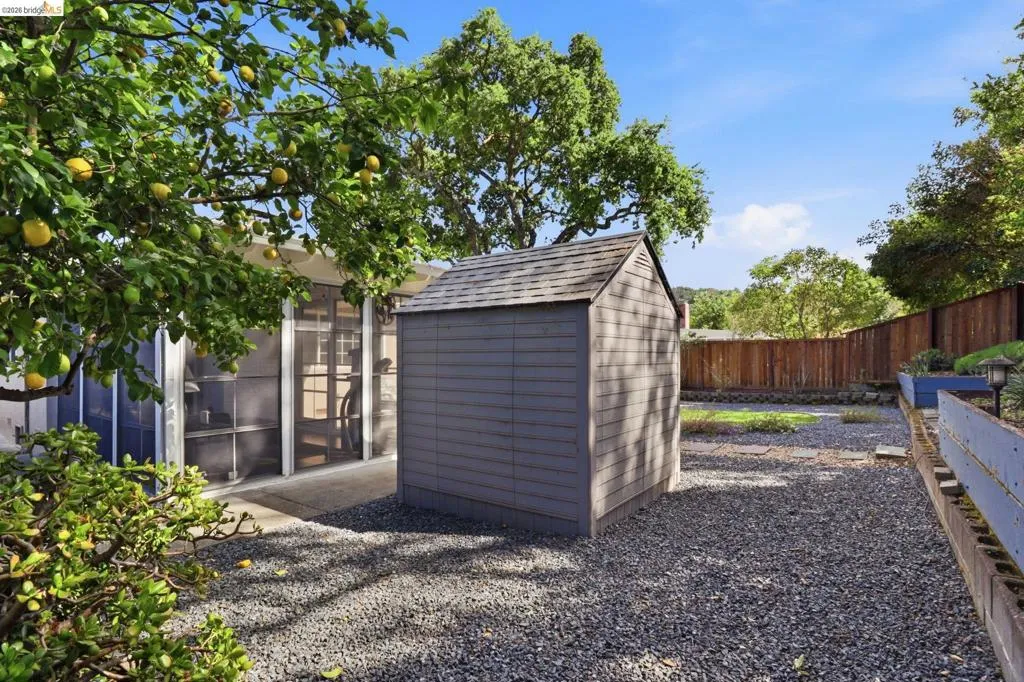 Backyard featuring a gray storage shed, a privacy fence, and a gravel-covered ground