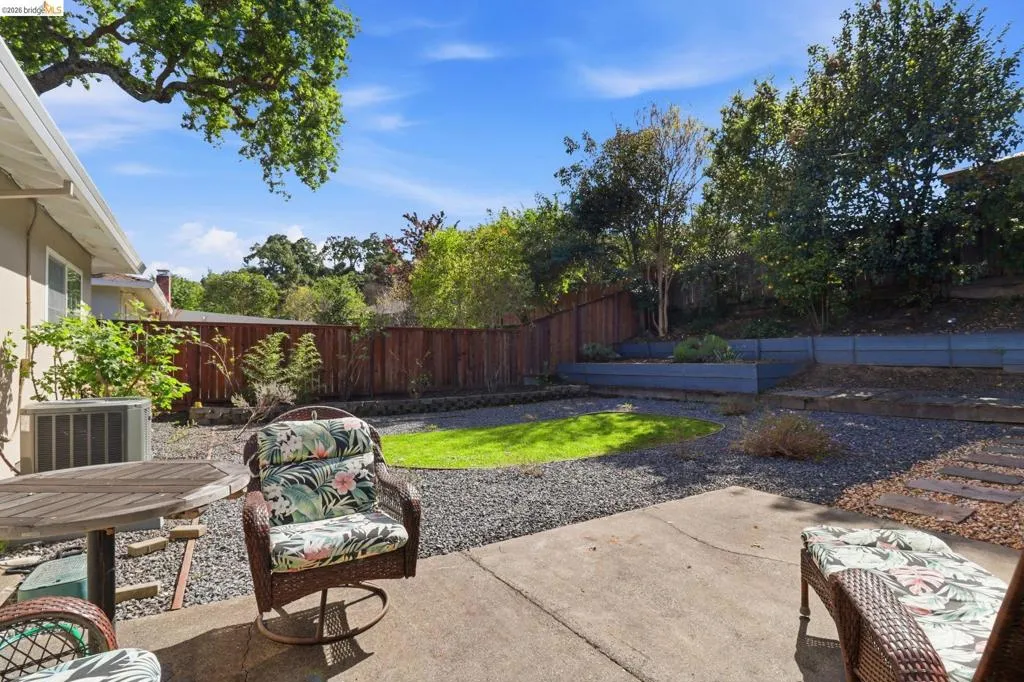 Private backyard with a concrete patio, gravel landscaping, and a central grass area