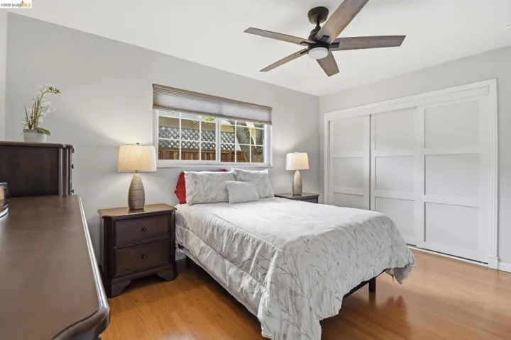 Interior room featuring wood-finish flooring, a ceiling fan with integrated lighting, and a window with blinds
