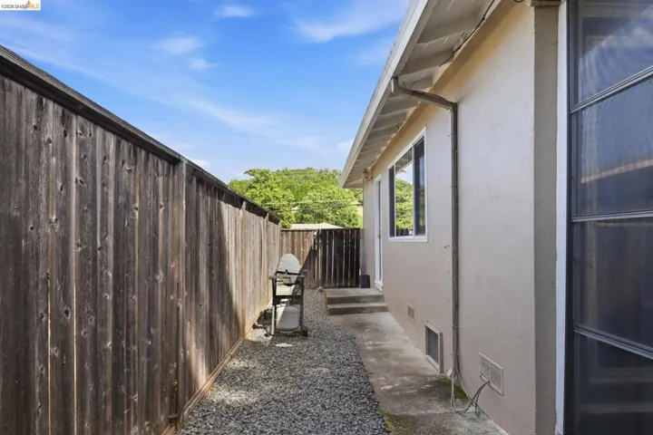 Side yard area featuring a gravel path and concrete walkway