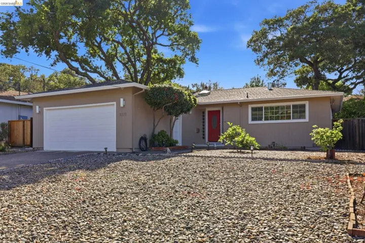 Single-story residence featuring a neutral exterior, white garage door, and a vibrant red entry door