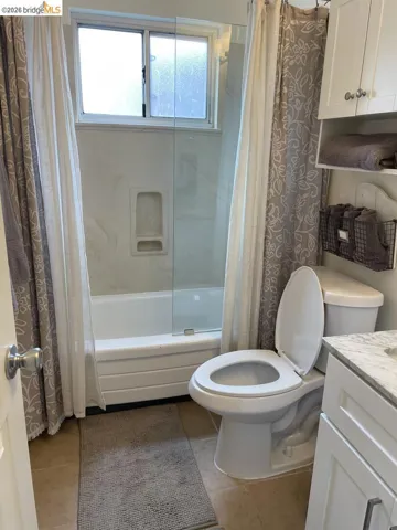 bathroom with shower / bathtub combination with curtain, vanity, and light tile patterned floors