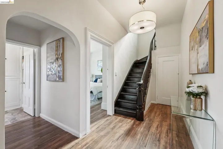 Entryway with arched walkways, dark wood-style floors, and stairs