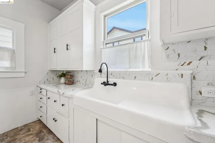 Kitchen with white cabinetry, tasteful backsplash, stone finish floors, and light stone counters