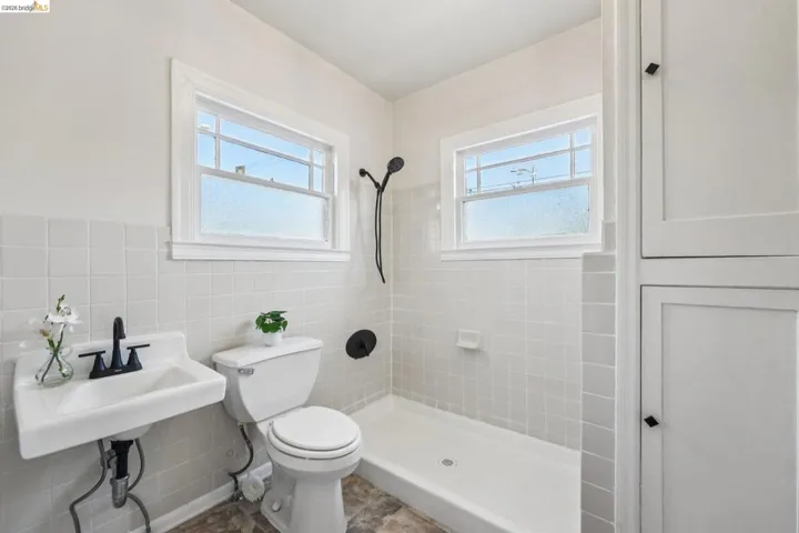 Bathroom with tile walls, a shower stall, and a wainscoted wall