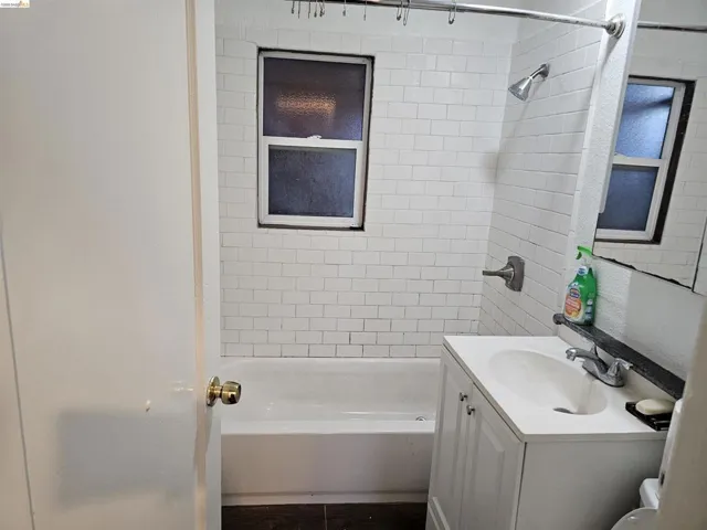 Bathroom featuring a white subway tile surround, a white bathtub, and a single-sink vanity with a white countertop
