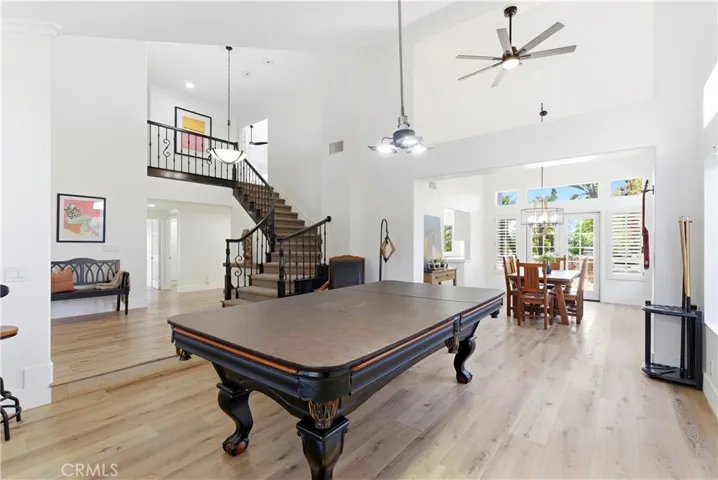 Bright and airy living space with soaring ceilings, elegant staircase, and abundant natural light, flowing seamlessly into the dining area.