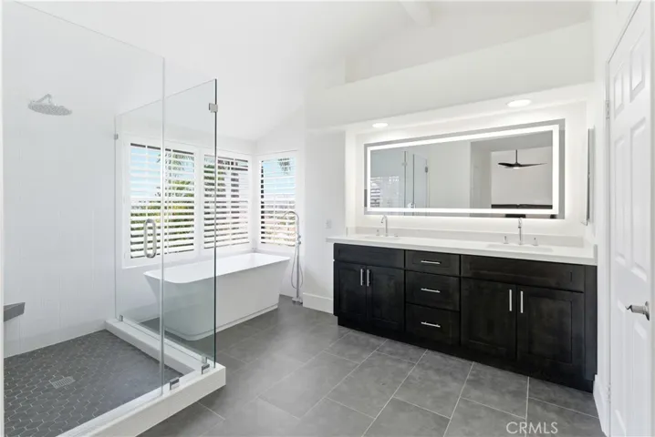 Beautifully remodeled primary bath featuring a freestanding tub, glass-enclosed shower, and dual sinks.