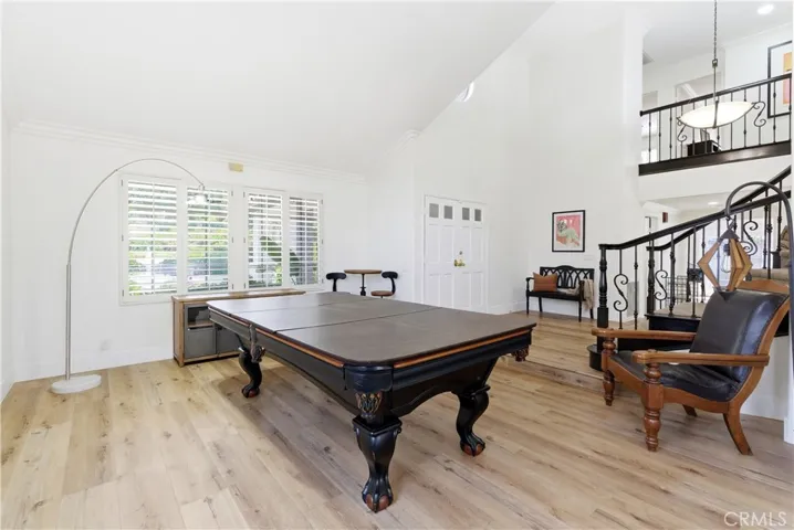 Bright and airy living space with soaring ceilings, elegant staircase, and abundant natural light, flowing seamlessly into the dining area.