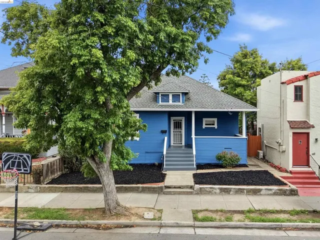 Charming blue exterior featuring a front porch with white columns, a gray shingle roof, and a dormer window