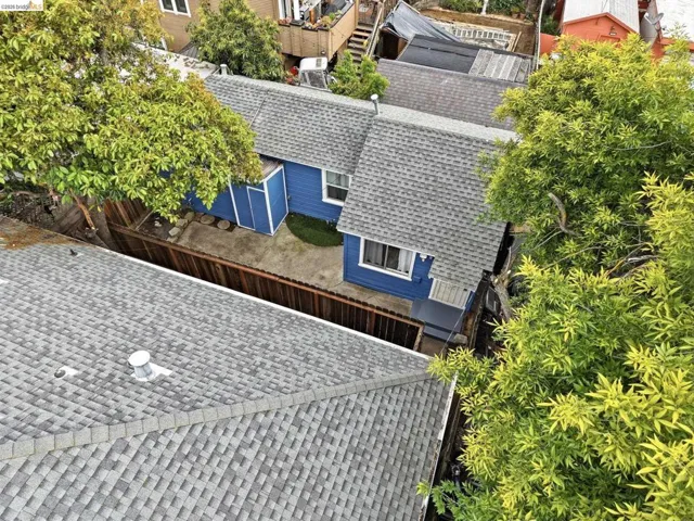Blue exterior residence featuring a gray shingled roof, white window trim, and a concrete patio space