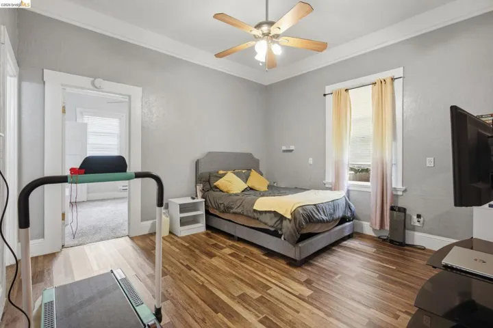 Wood-finish flooring throughout the room, complemented by a ceiling fan with integrated lighting